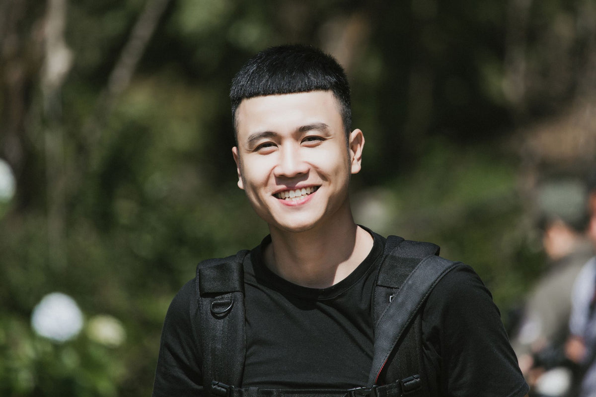Man in a plain black T-shirt smiling outdoors