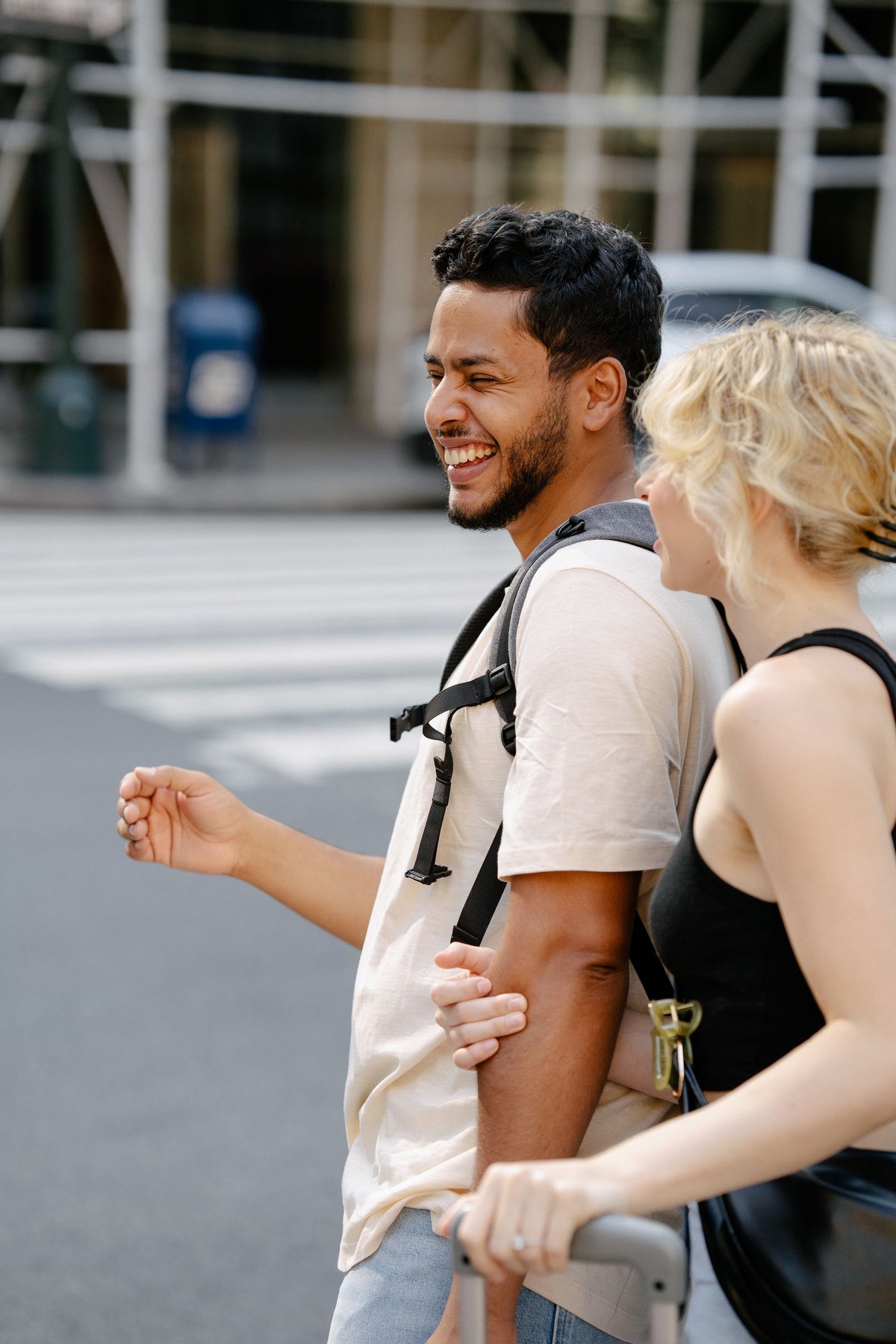 Man and woman laughing together while crossing a street