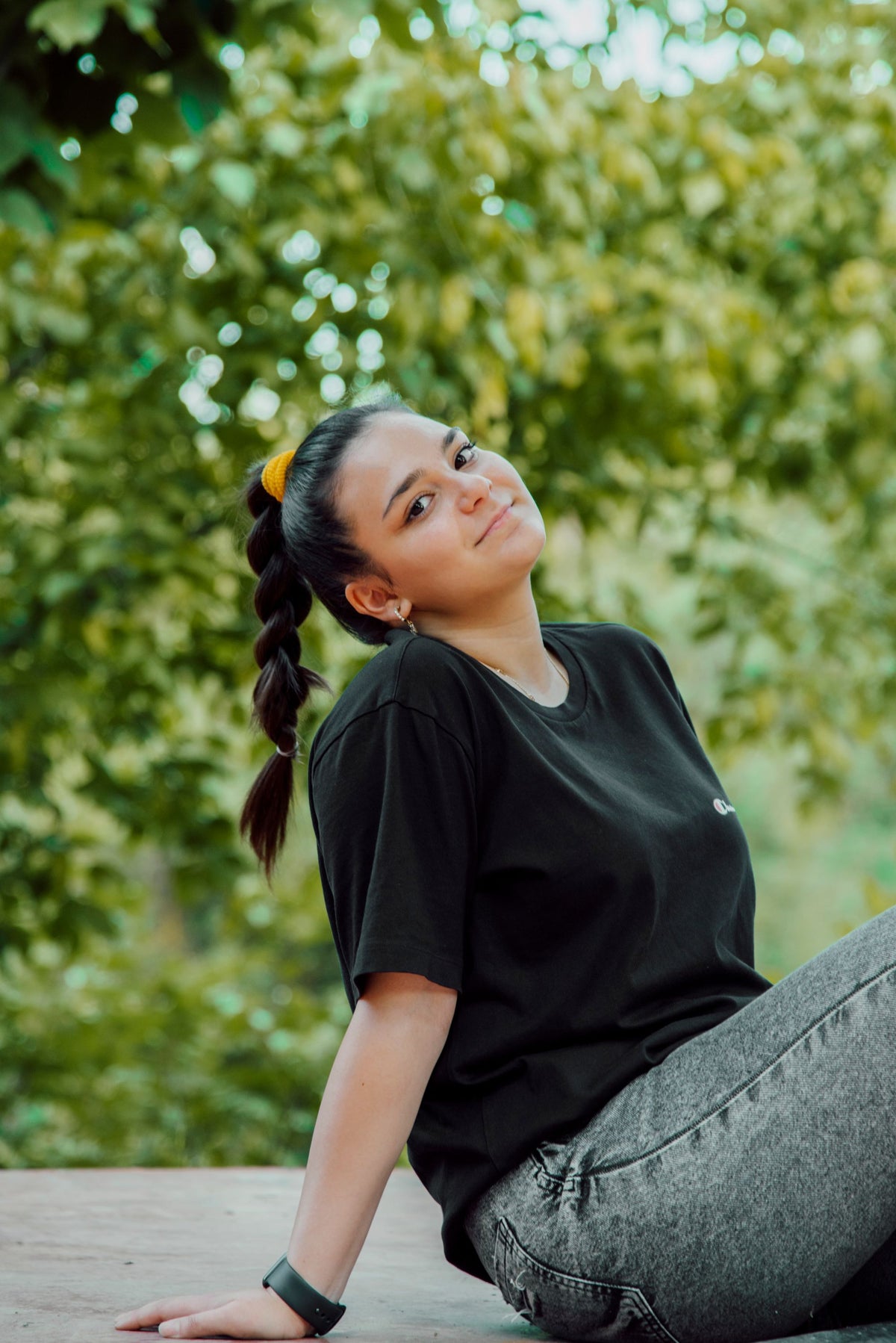 Woman in a casual black T-shirt sitting outdoors in green surroundings