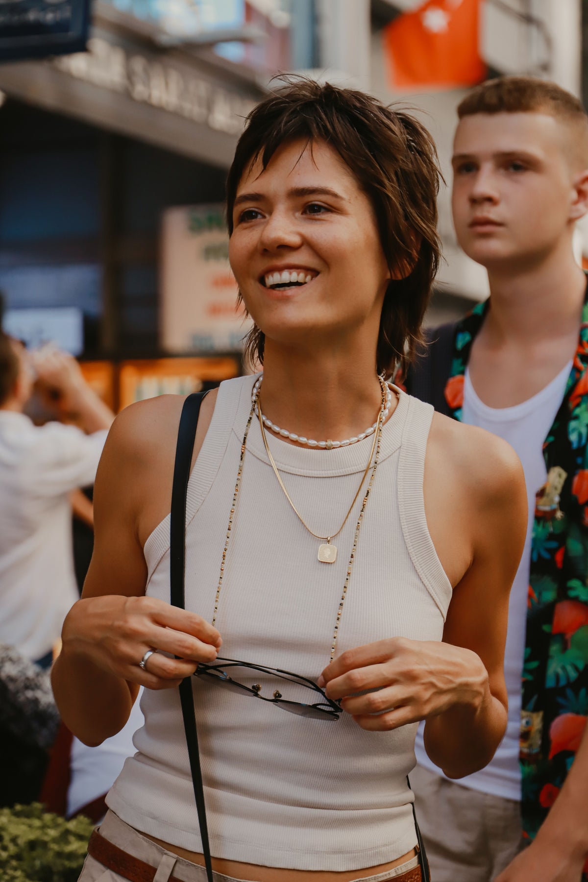 Smiling woman in a white tank top outdoors