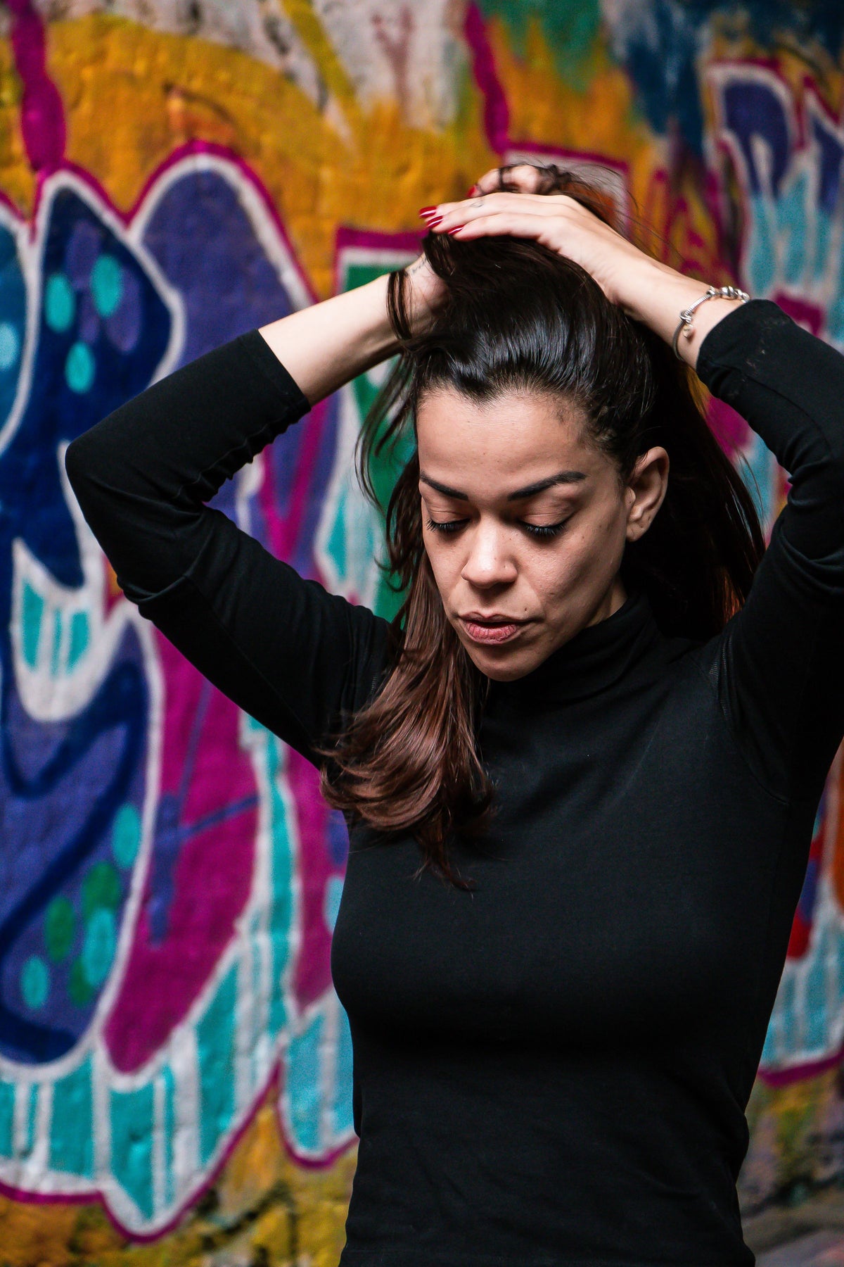 Woman in a black top in front of colourful London graffiti